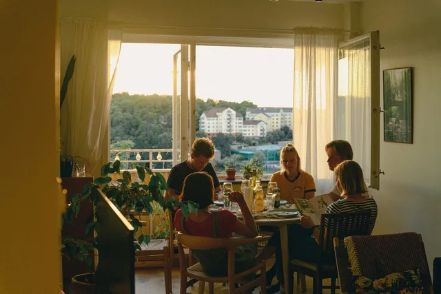 Friends sharing dinner around a table in a sunlit apartment